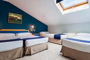 three beds in a room with a blue wall at Villa De Pinto in Pinto