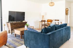 a living room with a blue couch and a table at Superbe villa avec piscine in Le Teich