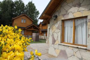 una casa con un montón de flores amarillas delante de ella en Complejo hotelero Illihue - Cabañas & Hostería en Junín de los Andes