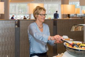 a woman standing in a kitchen preparing food at Hotel Asteria in Venray