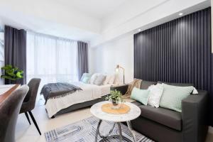 セブシティにあるFurnished Studio Rental in Prime Cebu IT Park with Gym, Pool, Fast WiFi and Netflixのベッドとソファとテーブルのある寝室