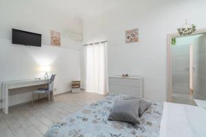 Un dormitorio blanco con una cama y un escritorio. en Dafne home, en Siracusa