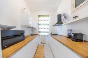 Una cocina con gabinetes blancos y una encimera de madera. en La casa di Anna, en Nettuno