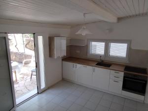 a kitchen with white cabinets and an open door at Beautiful Holiday House in Murter
