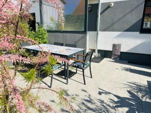 a table and chairs on a patio with pink flowers at Mon petit chez soi en Alsace in Rountzenheim