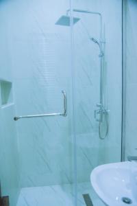 una ducha con una puerta de cristal junto a un lavabo en Cozy 4BDR Home with Snooker, 15mins from Airport, en Hausa