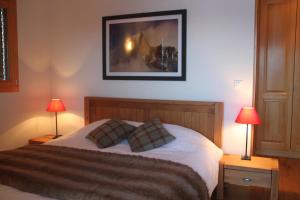 1 dormitorio con 1 cama con 2 lámparas y 1 foto en Chalet Alpage, en Anzère