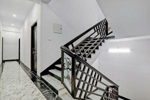 a staircase in a white building with a black railing at Hotel O The Lemongrass in Colonelganj