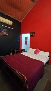 a bedroom with a large bed with a red wall at Swargam Pool Resort in Varkala