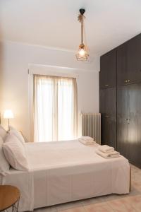 een slaapkamer met een groot wit bed met een raam bij ikosapartments-family in Pérdika +21 foto's