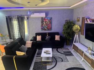 ンブールにあるAppartement privatif À Mbour face RN1のリビングルーム(黒いソファ、テレビ付)