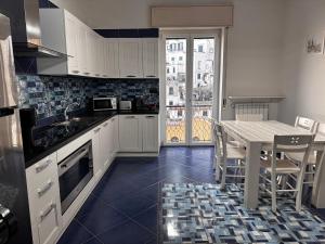 a kitchen with white cabinets and a table with chairs at Blue's House in Atrani