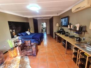 sala de estar con cama azul y cocina en Stay Eazi, en Piet Retief
