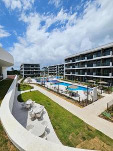 basen ze stołami i krzesłami oraz budynek w obiekcie Flat at Makia in Muro Alto Porto de Galinhas w mieście Porto de Galinhas