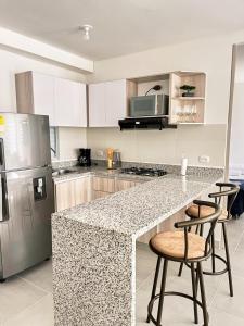 a kitchen with a counter with stools and a refrigerator at "Tu Escape en Cartagena" El Paraíso Caribeño! in Cartagena de Indias