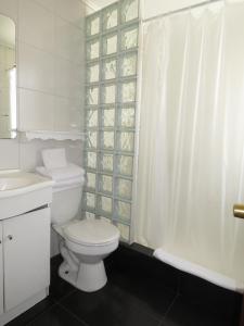 a white bathroom with a toilet and a shower curtain at Hotel La Fuente in Coquimbo