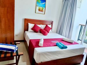 a bedroom with two beds with red and white pillows at Dreamwave Escape Nilaveli in Nilaveli +24 photos