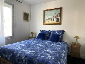 a bedroom with a blue bed with a blue comforter at La maison des écoliers in Deauville