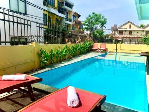 a swimming pool with a red table and chairs next to a building at ASAMI RIVERSIDE Hotel in Hoi An
