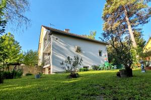 a white house with a gambrel in a yard at Bandiland Szigetmonostor Horány in Szigetmonostor