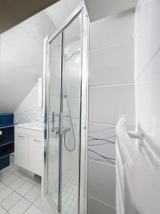 una doccia in vetro in un bagno bianco con lavandino di La Fraisnaie Omaha Beach a Saint-Laurent-sur-Mer
