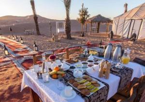 a table with food on it on the beach at Erg Sahara camp in Adrouine