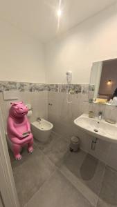 a bathroom with a pink pig sitting on the toilet at B&B Hotel Costa Azzurra in Spotorno