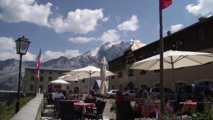 Leute, die vor einem Gebäude an Tischen mit Sonnenschirmen sitzen in der Unterkunft Berghotel Franzenshöhe in Trafoi