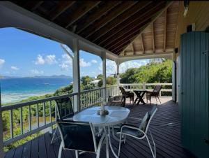 a porch with a table and chairs and the ocean at Blue Pearl Villa in St John USVI in Coral Bay