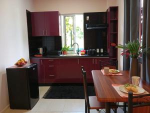 cocina con armarios rojos y mesa de madera en Dolfijn Studios, en Paramaribo
