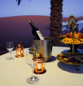 a table topped with a bottle of wine and candles at Merzouga Stars Luxury Camp in Merzouga
