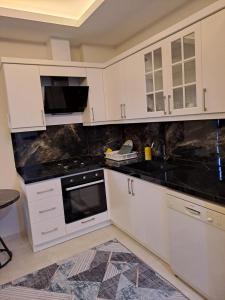 a kitchen with white cabinets and black counter tops at Neridabeachhomes 20 in Alanya