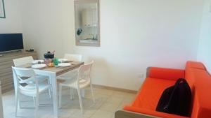 Un comedor con una mesa y sillas y un sofá. en Bilocale Delle Robinie in Baia Verde, en Baia Verde