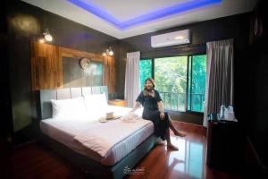 a woman sitting on a bed in a bedroom at นาธาริเวอร์ไซด์ in Ban Lamphu La (3)