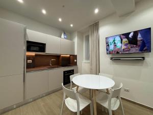 a kitchen with a white table and a tv on a wall at Bella Como Holiday Apartment in Como +4 photos