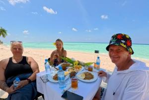 a group of people sitting at a table on the beach at Fishing Tours Maldives in Thimarafushi