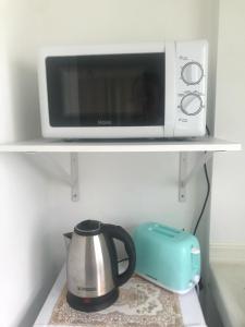 a microwave and a coffee pot on a shelf at Chiltern cottages in Amphoe Koh Samui