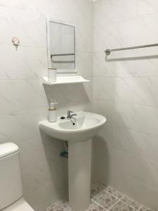 a white bathroom with a sink and a toilet at Chiltern cottages in Amphoe Koh Samui
