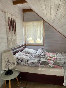 a bed in a room with a window and a table at Agroturystyka Eden i Raj "Pod rzeźbami" in Krynki