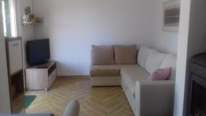 a living room with a white couch and a tv at Kuća Mare, 130m od mora in Seline