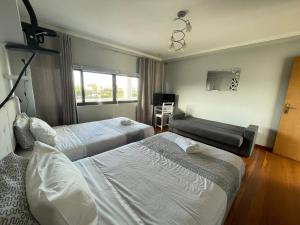 a hotel room with two beds and a television at Surf & Guest Lorena´s House in Ribeira Grande