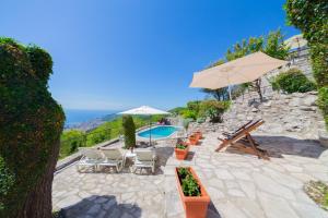 a patio with a pool and chairs and an umbrella at Villa Rustique in Budva