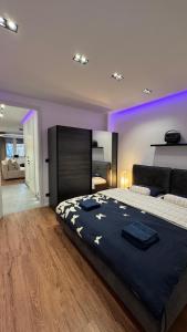 帕尔杜比采Moderní Hi-Tech apartmán v centru Pardubic - Wi-Fi, Netflix, projektor的一间紫色照明客房内配有一张大床的卧室
