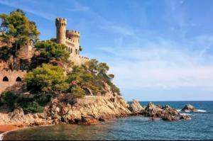 a castle on an island in the water at Costa Suite Beach, Pool and Parking in Lloret de Mar