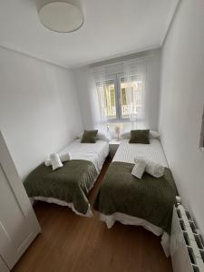 two beds in a room with white walls and wooden floors at Casa Mouro Somo - Surf y playa in Somo