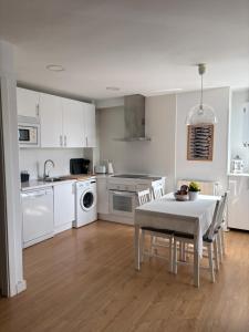 a kitchen with white cabinets and a table and chairs at Casa Mouro Somo - Surf y playa in Somo