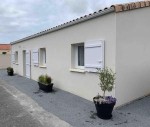 a white building with potted plants in front of it at LIL de SAND in Bourcefranc