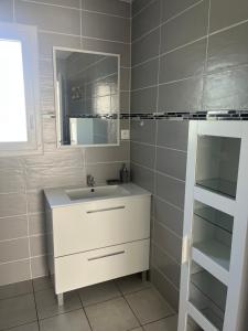a bathroom with a sink and a mirror and shelves at LIL de SAND in Bourcefranc