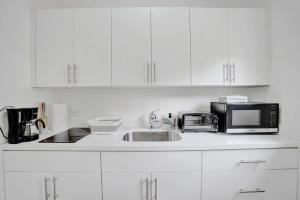 Una cocina con gabinetes blancos, un fregadero y un microondas. en Central Stunning Villa with Heated Pool Cabana, en Hollywood Ridge Farms
