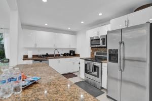 Una cocina con gabinetes blancos y electrodomésticos de acero inoxidable. en Central Stunning Villa with Heated Pool Cabana, en Hollywood Ridge Farms